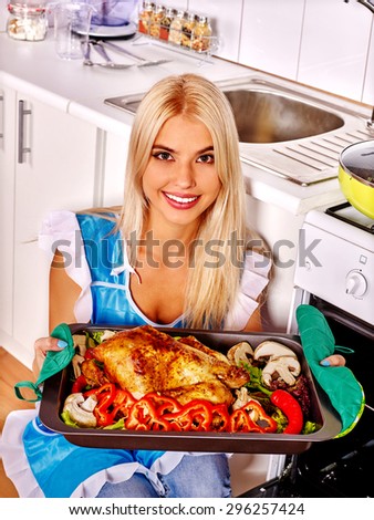 Young woman cooking big grill chicken at kitchen.