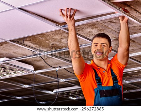 Man in builder uniform hand up  installing suspended ceiling