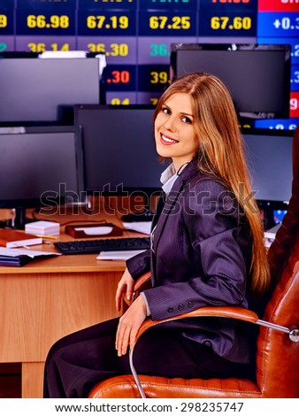 Business woman with  stock exchange board looking at camera in office.