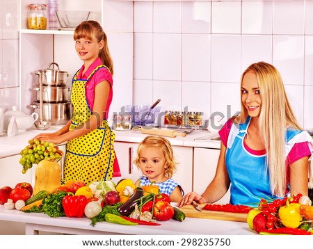 Mother and two beautiful  daughter cooking food at kitchen.