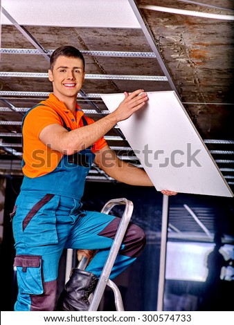 Man in builder uniform installing suspended ceiling