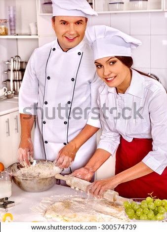 Happy woman and man in chef hat cooking dough .Grapes in foreground
