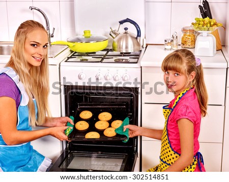Mother and daughter bake cookies in oven . Kitchen.