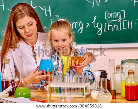 Child and woman holding flask in school class. Chemistry teacher