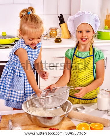 Child with rolling-pin dough at kitchen. Kids cooking at home