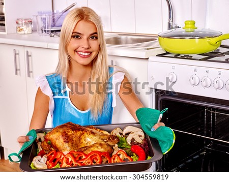 Girl cooking chicken on kitchen. Woman cooking at home.