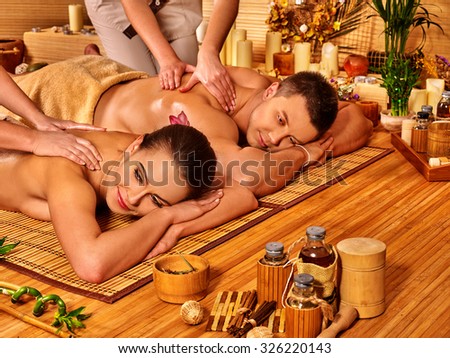Man and woman relaxing in bamboo  spa interior on wooden floor.