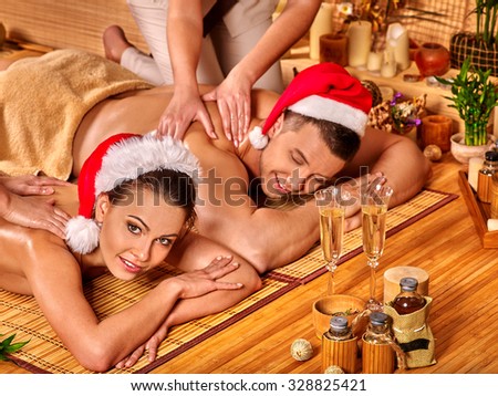 Man and woman wearing Christmas hat having massage. Concept Xmas spa.