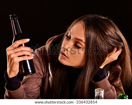 Drunk girl looking at bottle of alcohol. Soccial issue alcoholism.