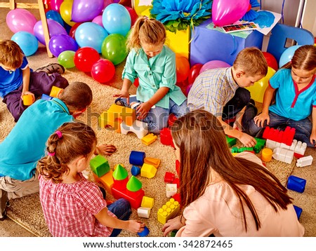 Group children game blocks and balloons on floor in kindergarten . Top view.