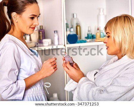 Woman middle-aged in spa salon with young beautician before procedure .