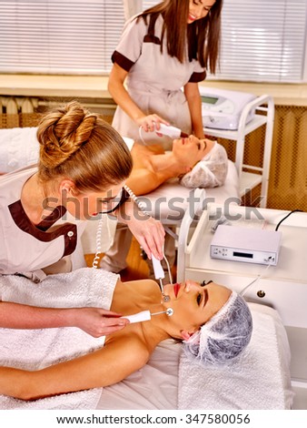 Group of women receiving electric galvanic face spa massage procedure  at beauty salon.