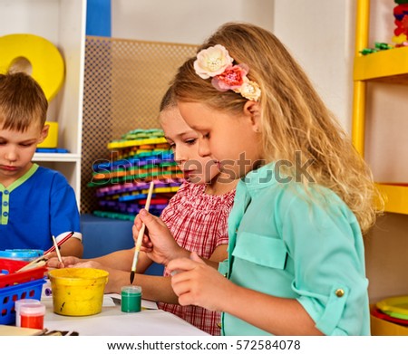 Small students painting in art school class. Child drawing by paints on table. Boy and girls in kindergarten. Drawing education develops creative abilities of children.