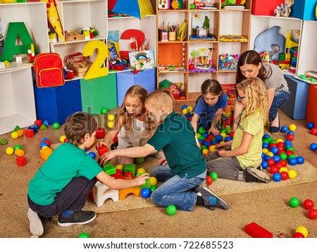 Children building blocks in kindergarten. Group kids playing toy on floor. Top view of interior preschool. Building a tower of cubes. Logical constructor.