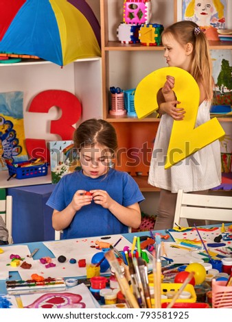 Child dough play in school. Plasticine for children. mold from plasticine in kindergarten. Kids knead modeling clay with hands in preschool. Girl indulges during lesson.