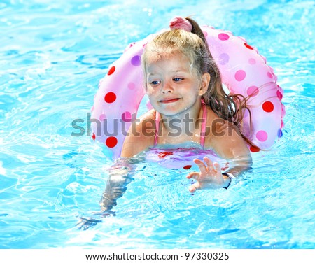 Little girl sitting on inflatable ring in swimming pool.