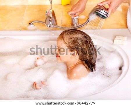 Little girl washing hair in bubble bath.