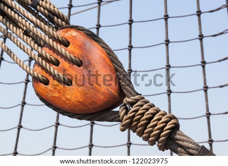 a tall ship detail showing 19th century wooden block and tackle with hemp rope for sail adjustment