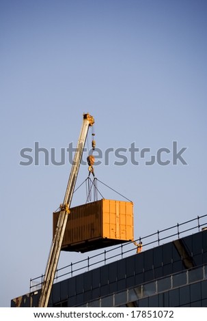container being lifted to a building top by a crane