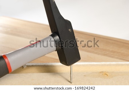 hammer nailing a nail into wood