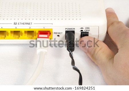 hand in foreground connecting a router to internet white