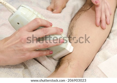 Beautician while making a male waxing with wax strips.