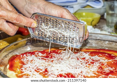 Hands on first plane using a grater, grate cheese for a pizza