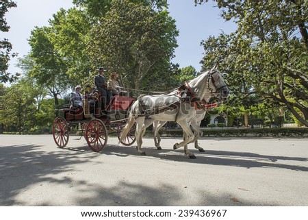 SEVILLE, SPAIN - MAY 7: Tourists riding on horse carriage walking in the Park of Maria Luisa on may 7, 2014 in Seville.