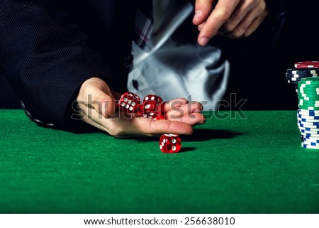Male hand rolling five dice on green felt