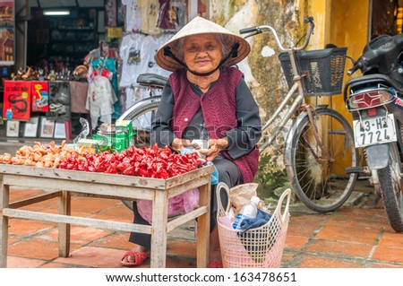 HOI AN, VIETNAM - NOVEMBER 26,2009 - Old woman in traditional Vietnamese hat sells souvenirs in Hoi An.
