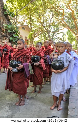 AMARAPURA, MYANMAR - NOVEMBER 23,2009 - Young monks begging for alms.Each boy must pass some time in monastic robes, while attending school.