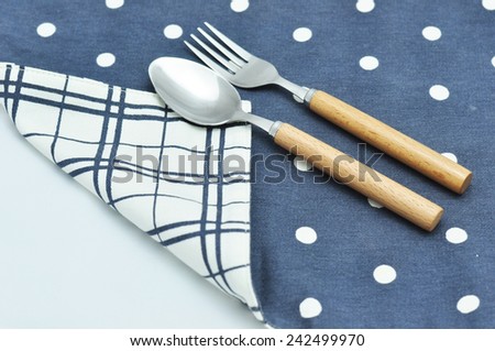 Spoon and fork on blue table linen polka dot