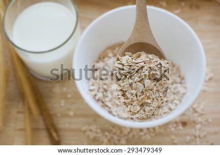 Oat Flake Oat Flake in wooden spoon and white bowl with glass of milk