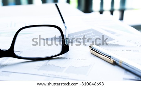 Soft Focus Pen and eyeglasses on blur newspaper background
