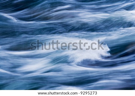 Water rushing by in river forming a painted appearing abstract pattern.