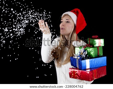 Winter woman with gifts blowing christmas snow from hands, isolated on black.