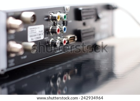 Horizontal Picture of rear side of music and video player with focus on color audio connectors in two rows and with visible reflection in the surface of bottom board