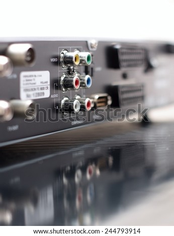 Vertical Picture of rear side of music and video player with focus on color audio connectors in two rows and with visible reflection in the surface of bottom board
