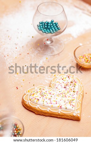 Decorating home-made cookies with sprinkles on wooden pastry board. Perfect for Mother\'s Day, Valentines or wedding related content.