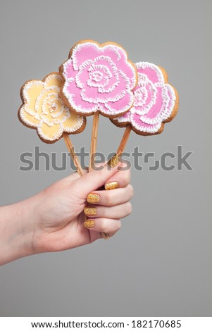 Hand holding a bunch of unusual flowers - rose shaped cake pops decorated with royal icing. Perfect for Mother's Day, Valentines, birthdays or wedding related content.