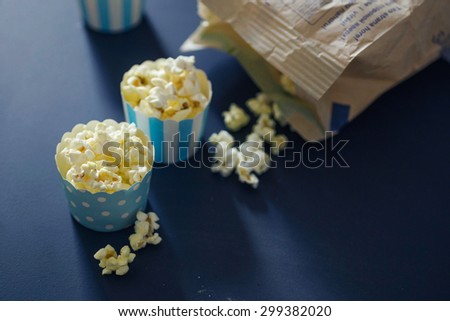 Three cupcake cases filled with salty caramel popcorn on chalkboard background. Fun snack for a children party or a movie night. Selective focus, bokeh, subtle grain and toning.