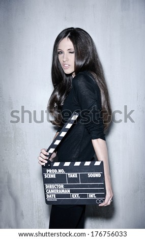 Full portrait of sensuality woman with beautiful long dark hair, posing at studio, wearing black, holding clapperboard