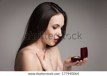 Surprised beautiful woman holding jewelry box with an engagement ring in it. Happy young woman after marriage proposal.