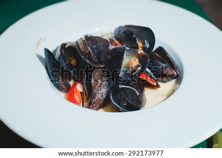 Boiled mussels on white plate in white wine sauce