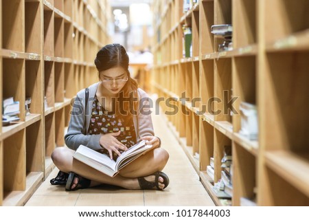Education-a girl are sitting to read a book in library ,she study hard for her exam -a girl 's serious to read book-the knowledge from library