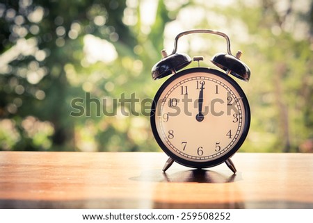 Retro alarm clock on table and nature background.