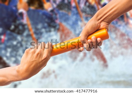 hands passing a relay baton on rowing team background