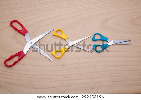 Three scissors like idiom Big fish eat little fish in the business on wooden texture.