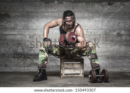 portrait of aggressive muscle man lifting weights on wall background