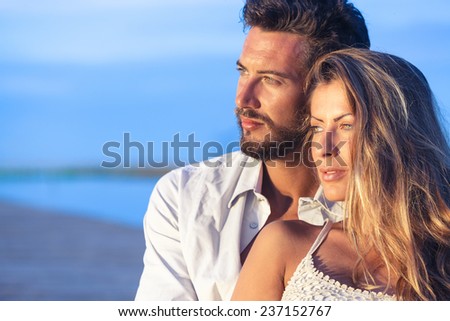 Portrait of a man embracing his woman from behind on seaside background under a blue sky